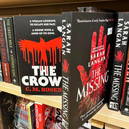 Women In Horror signed by Canelo Books The Crows by CM Rosens on a bookshelf next to The Missing by Sarah Langan